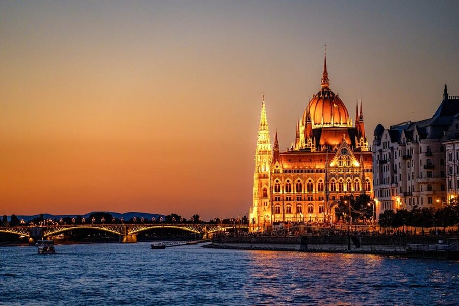 The Hungarian Parliament lit along the Pest embankment at dusk
